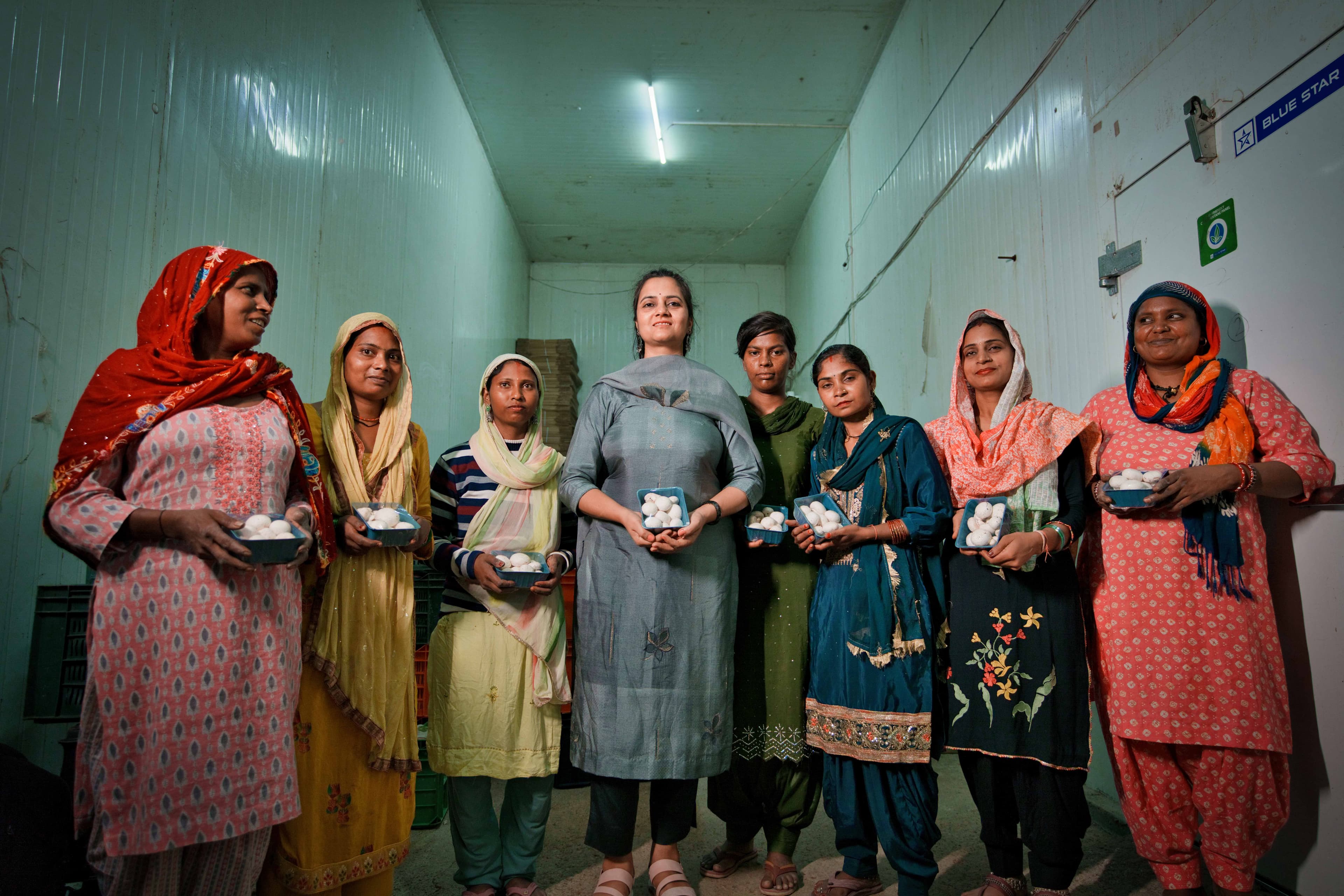 Group of women in traditional dress learning mushroom cultivation